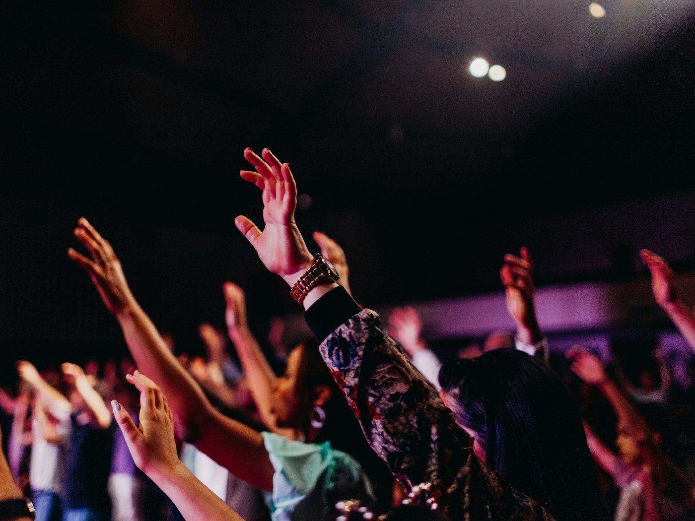 Hands raised together in worship at a gathering